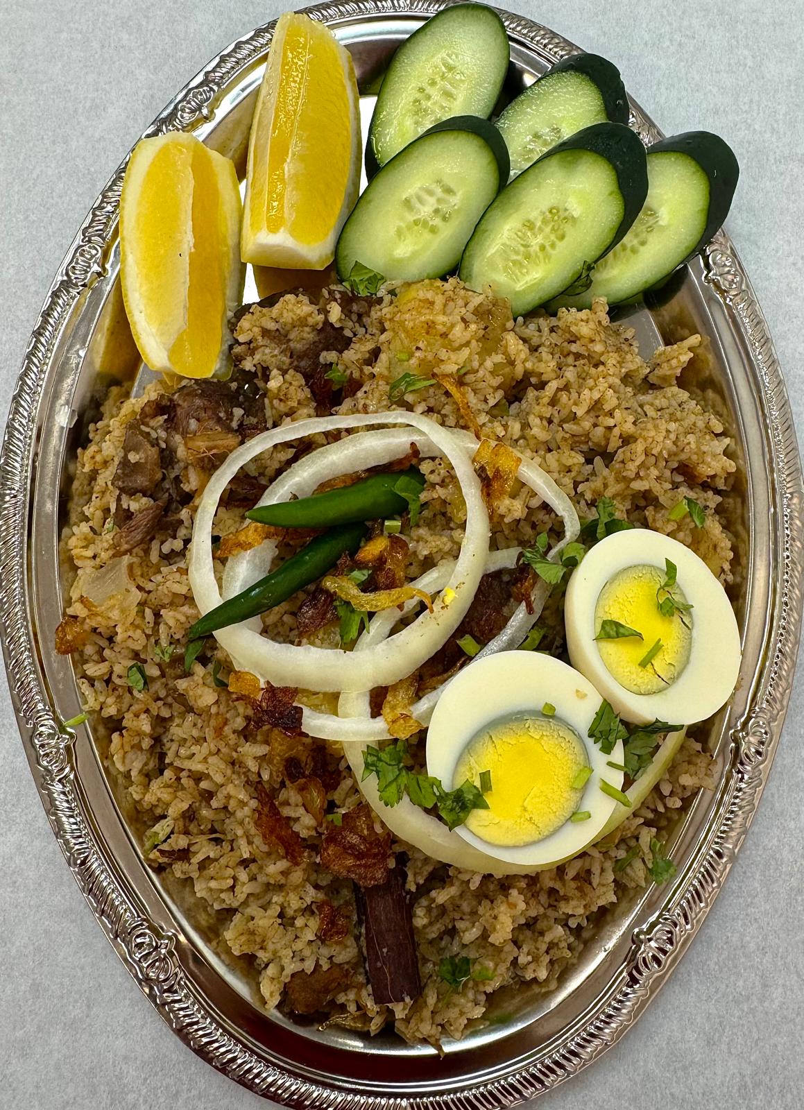 Bengali beef tehari served in a copper plate with egg and salad